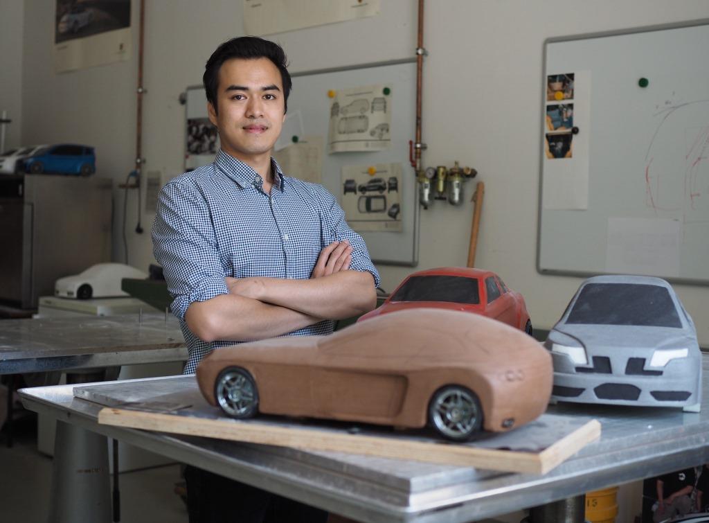 
                                Male student posing with model cars
                            