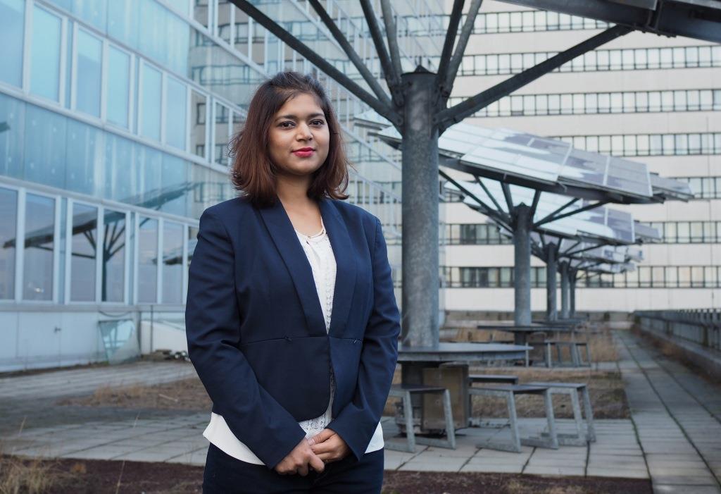 
                                Female student standing in front of solar pabels at a university campus
                            