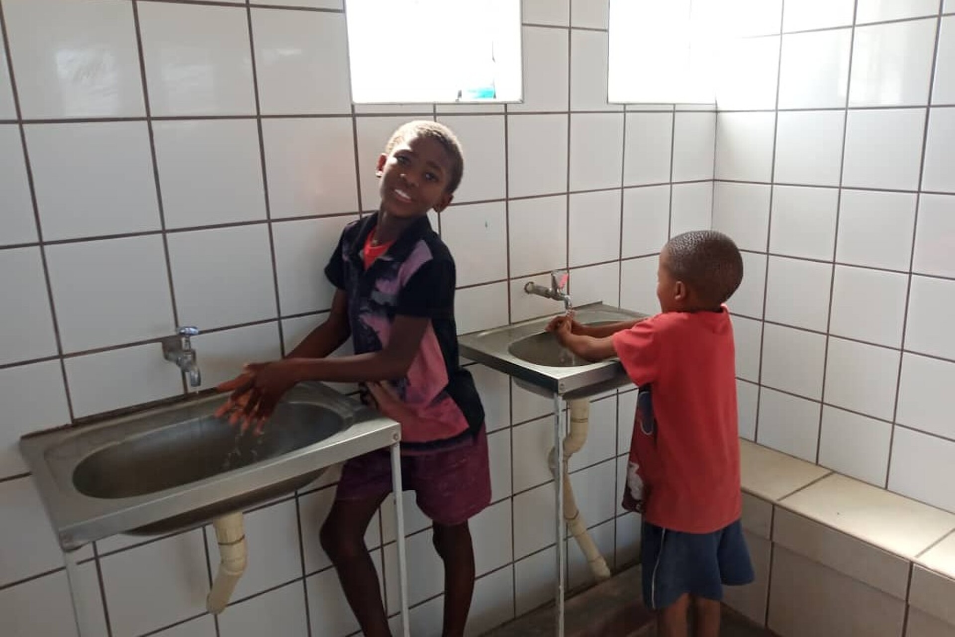 Zwei Schulkinder waschen sich im Waschraum die Hände