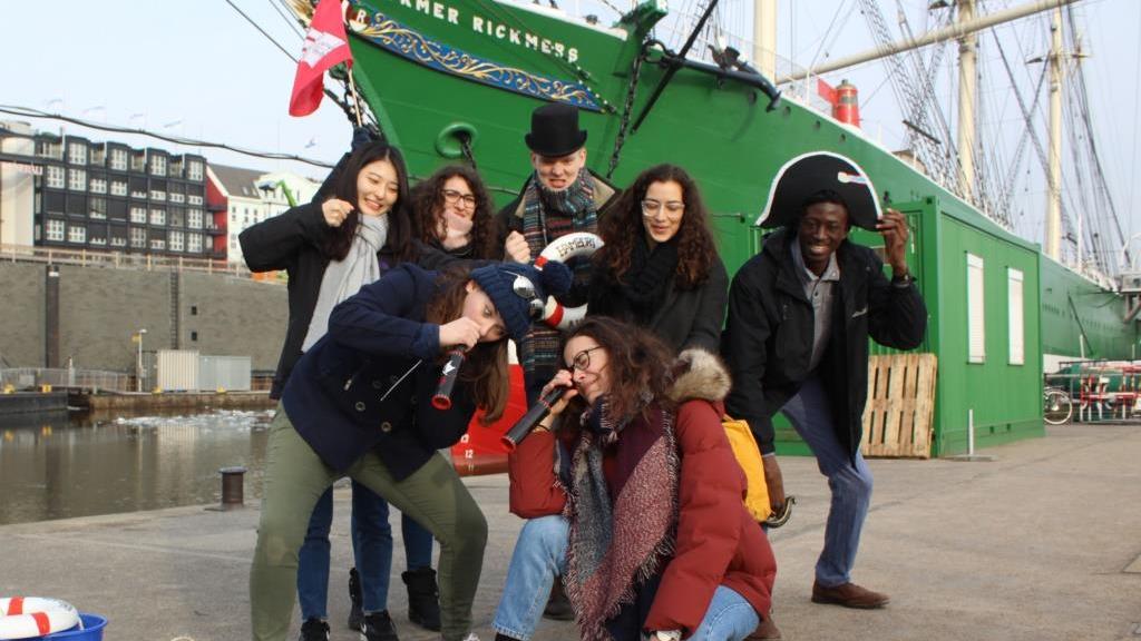 Group of students dressed as pirates in front of a sailing boat