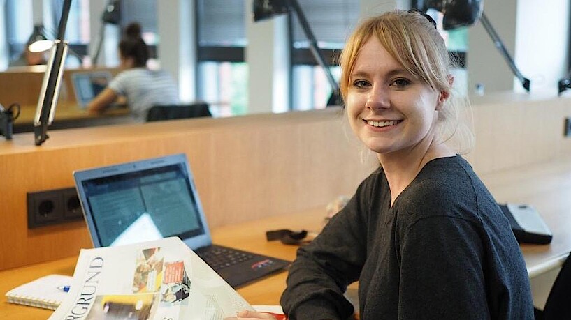 Smiling student sitting at a desk in the university library