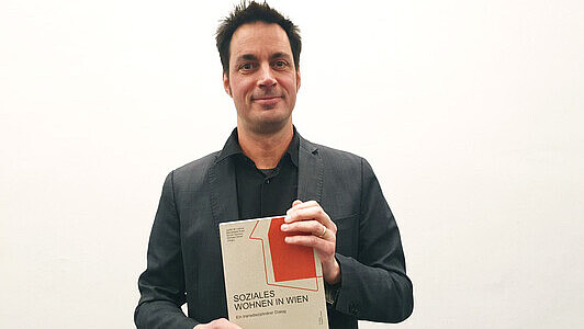 Prof. Simon Güntner hält den Sammelband in den Händen, für den er eine Auszeichnung erhalten hat