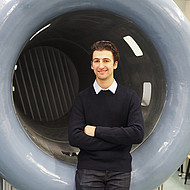 Male student standing in front of a wind tunnel