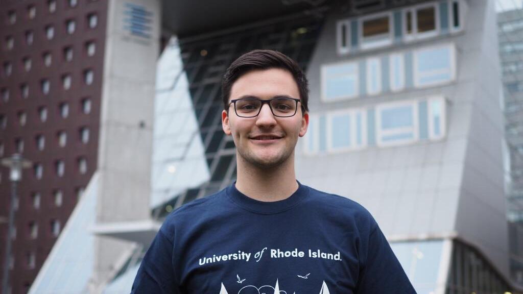 Male student smiling in front of university building