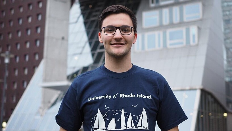 Male student smiling in front of university building