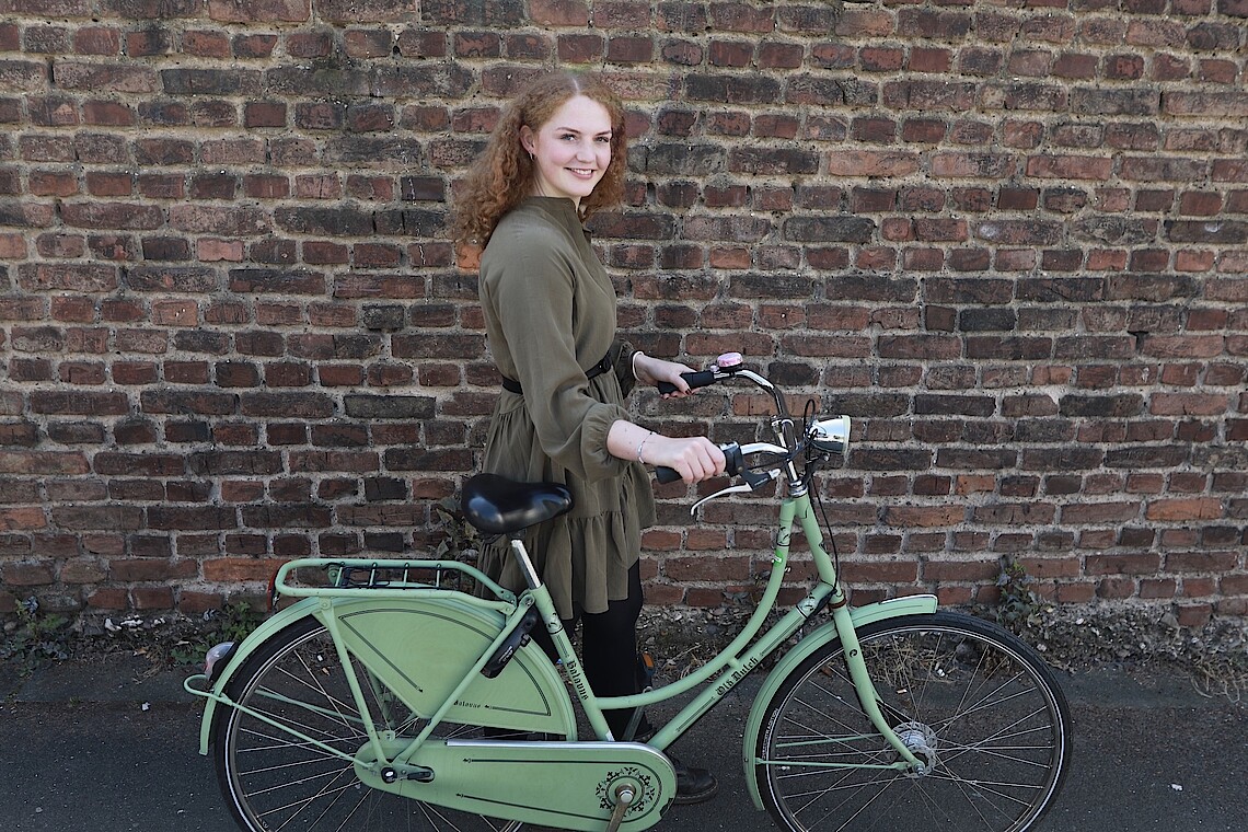 Sophie Kregel mit Fahrrad vor einer Backsteinwand
