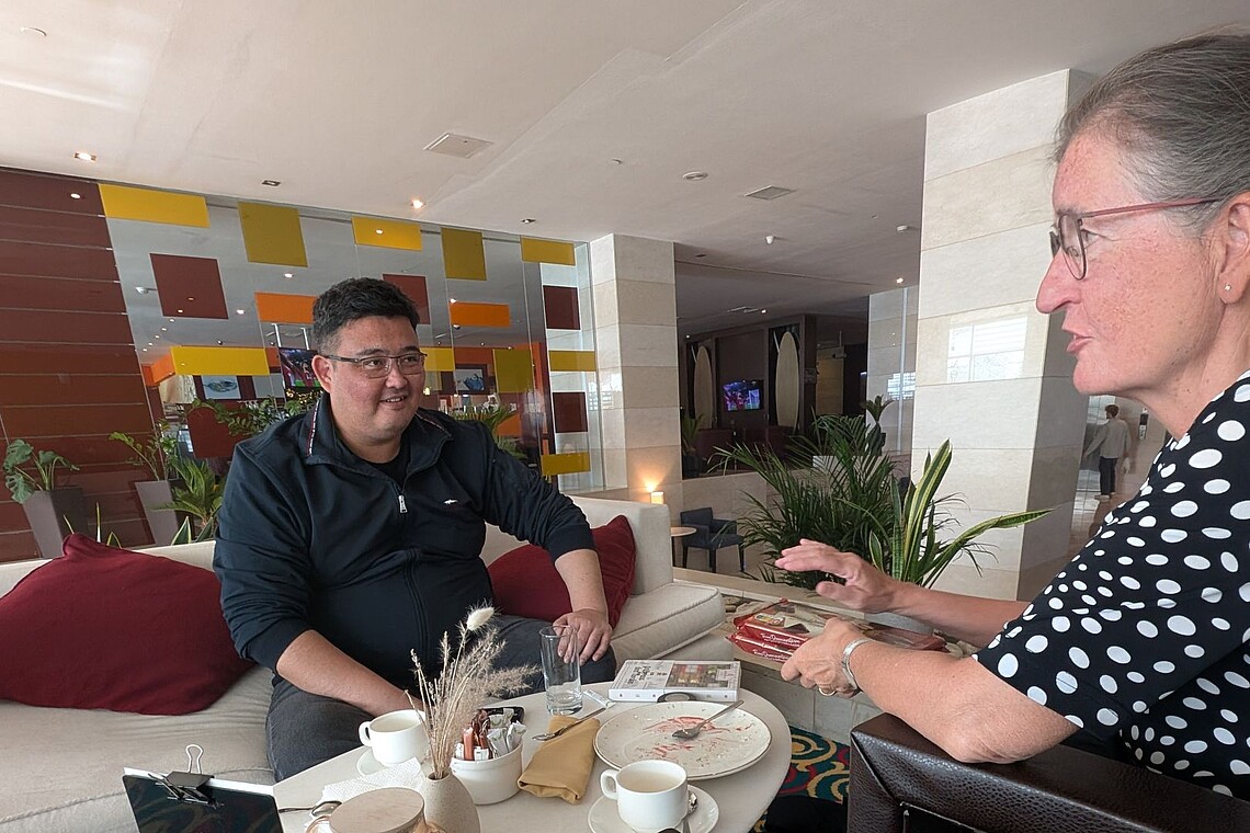 Zwei Personen unterhalten sich bei Heißgetränken und Nachtisch