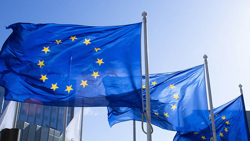 Drei Flaggen mit dem Europa-Sternenkreis vor blauem Himmel