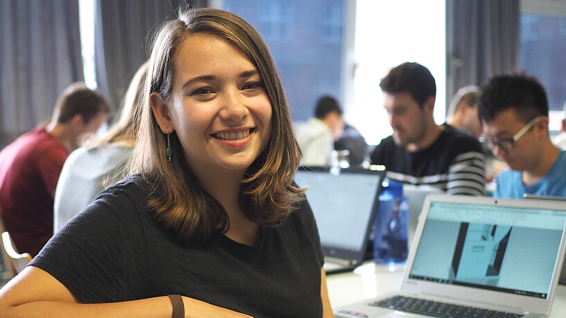 female student sitting at desk with other students