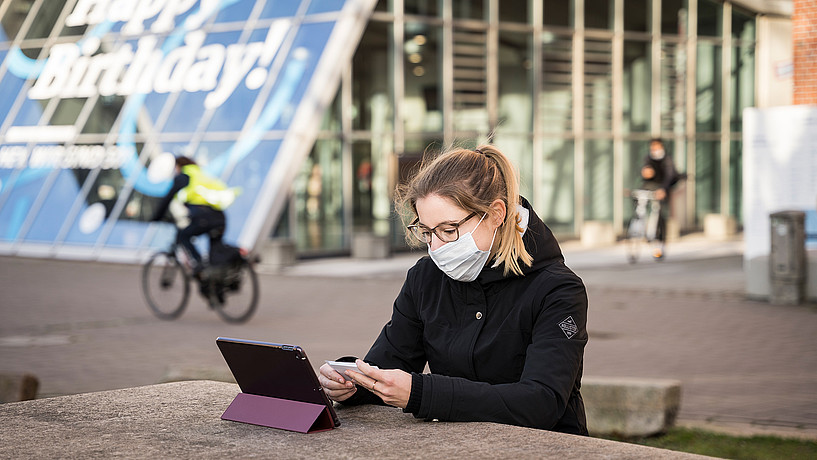 Studentin mit Mundschutz vor einem Laptop auf dem Campus Berliner Tor
