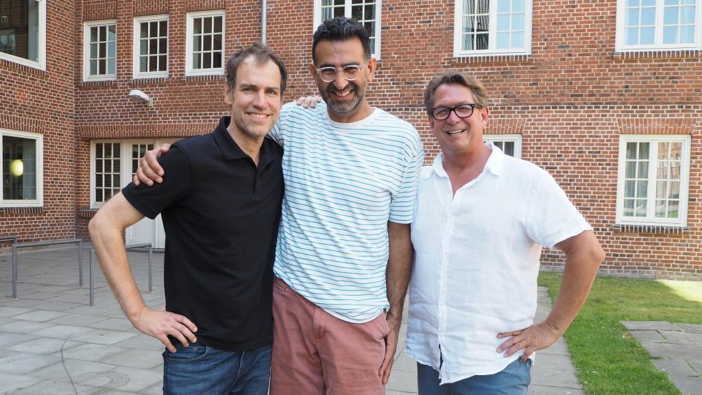 Three professors standing in front of a university building