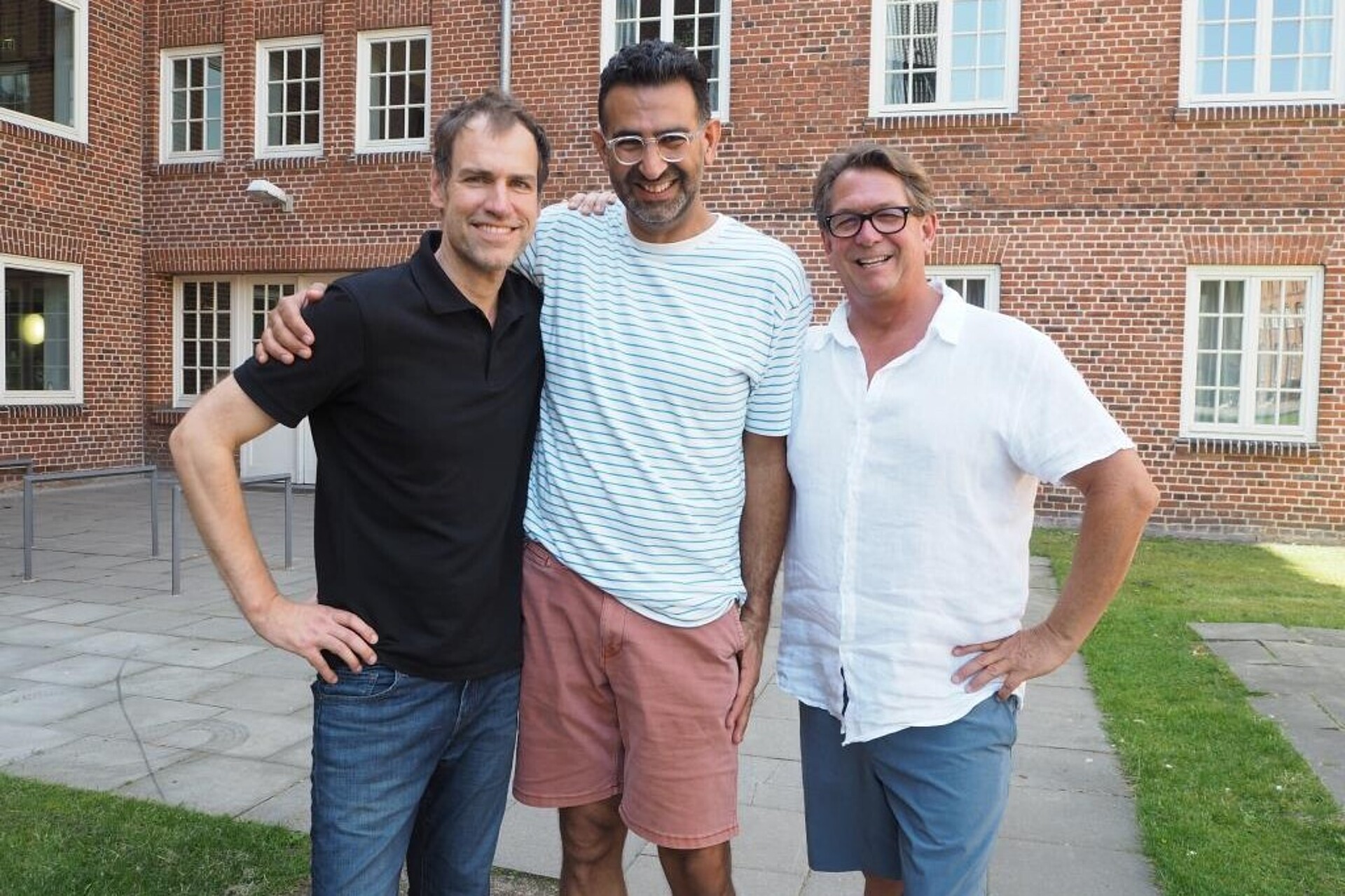 
                                                Three professors standing in front of a university building
                                            