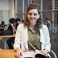 Female student sitting with a book in a university lobby