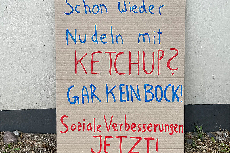 Demonstrationsplakat an einer Wand angelehnt - "schon wieder nur Nudeln mit Ketchup? Gar kein Bock! Soziale Verbesserung jetzt