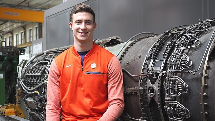 Smiling student in front of an aircraft engine