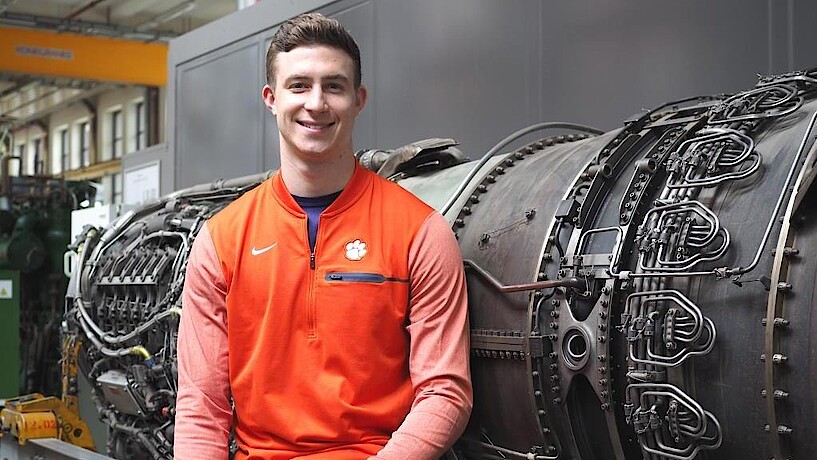 Smiling student in front of an aircraft engine
