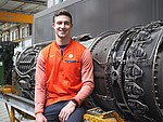 Smiling student in front of an aircraft engine