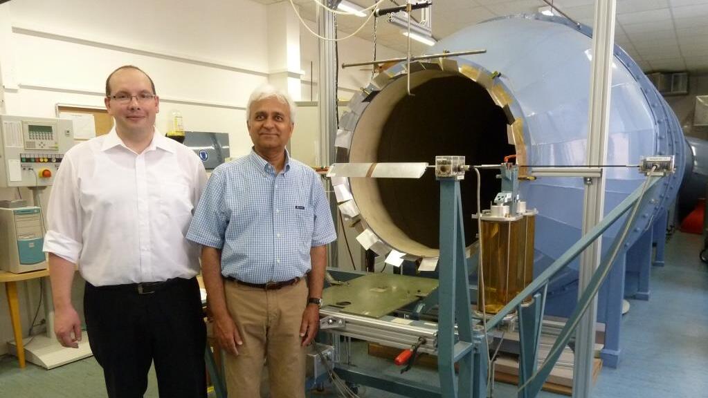 Two male professors in front of a wind tunnel