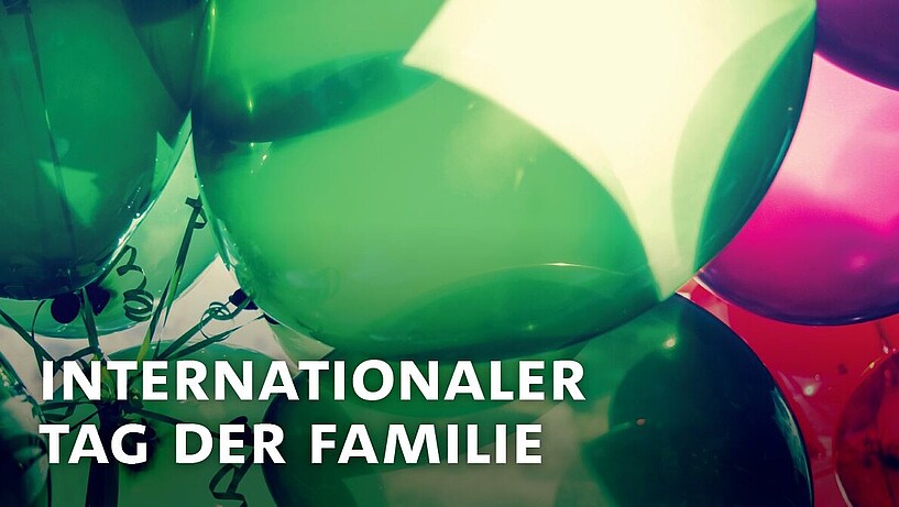 Das Bild zeigt den Schriftzug "Internationaler Tag der Familie" und im Hintergrund eine Reihe bunter Luftballons.