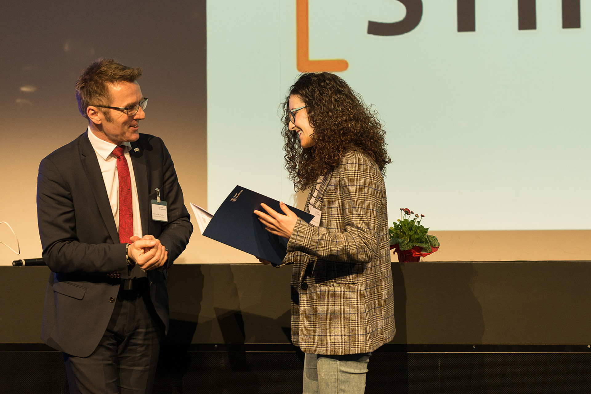Hochschulpräsident der HAW Hamburg, Prof. Dr. Micha Teuscher überreicht eine Stipendienurkunde