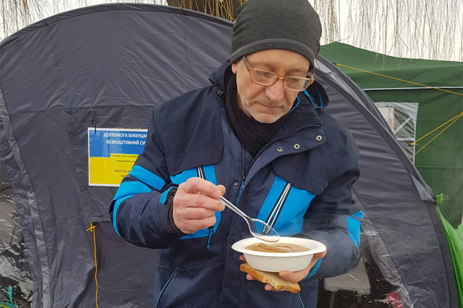 
                                                Dimitri Becker bei einer Pause mit einem Suppenteller in der Hand
                                            