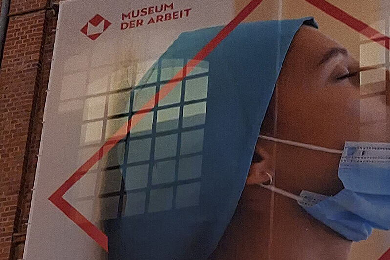 An der Außenwand des Museums der Arbeit befestigtes Plakat zur Ausstellung CARE! – Wenn aus Liebe Arbeit wird