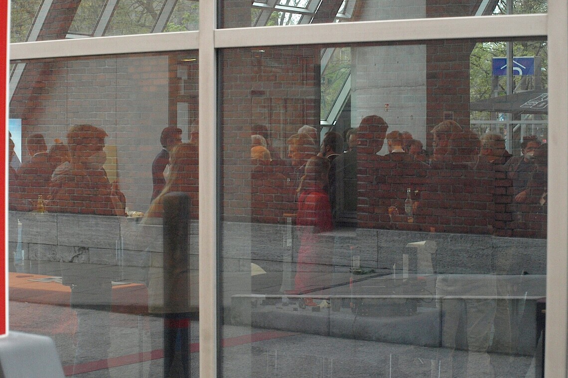 Personen beim Get together von außen durch eine Scheibe fotografiert