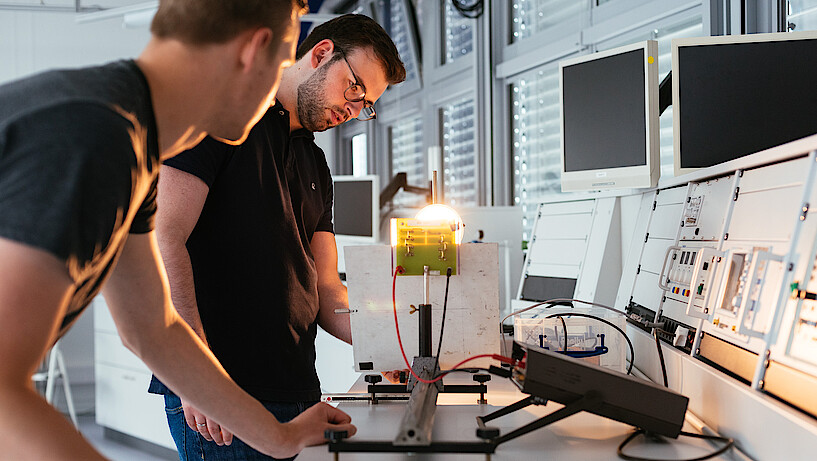 Zwei Studenten im Physiklabor bei einem Experiment.