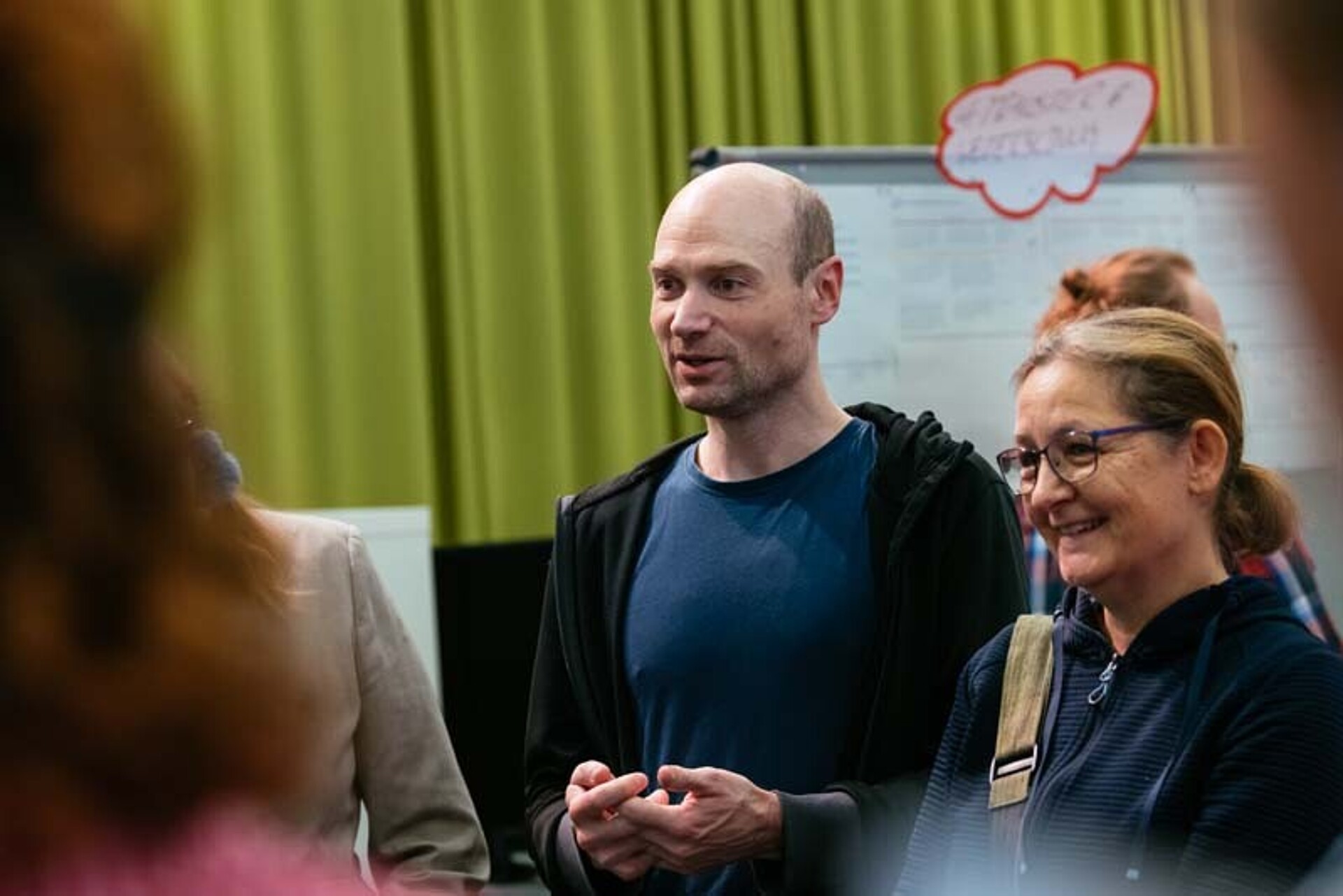 
                                                Zwei Teilnehmende hören zu
                                            