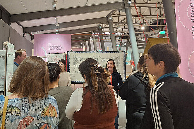 Der Gruppe werden von einer Museumsführerin die Ausstellungsobjekte zum Thema „Unbezahlte Care-Arbeit“ erläutert. 