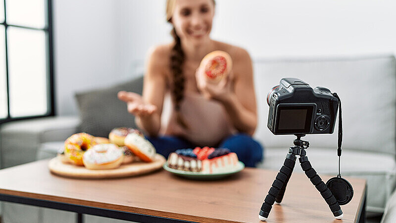 Influencer-Frau mit Zuckerprodukten vor einer Kamera