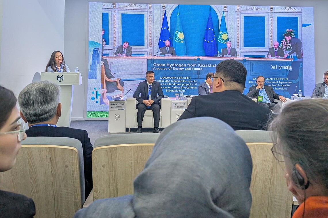 Studierende und Lehrende schauen einer Präsentation zu.