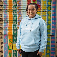 Female student smiling into the camera in front of a brightly painted container