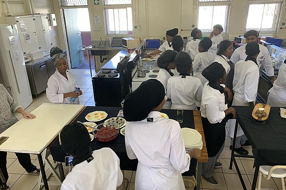 Studierende stehen in einem Hörsaal und haben einen gemeinsamen Koch-Workshop