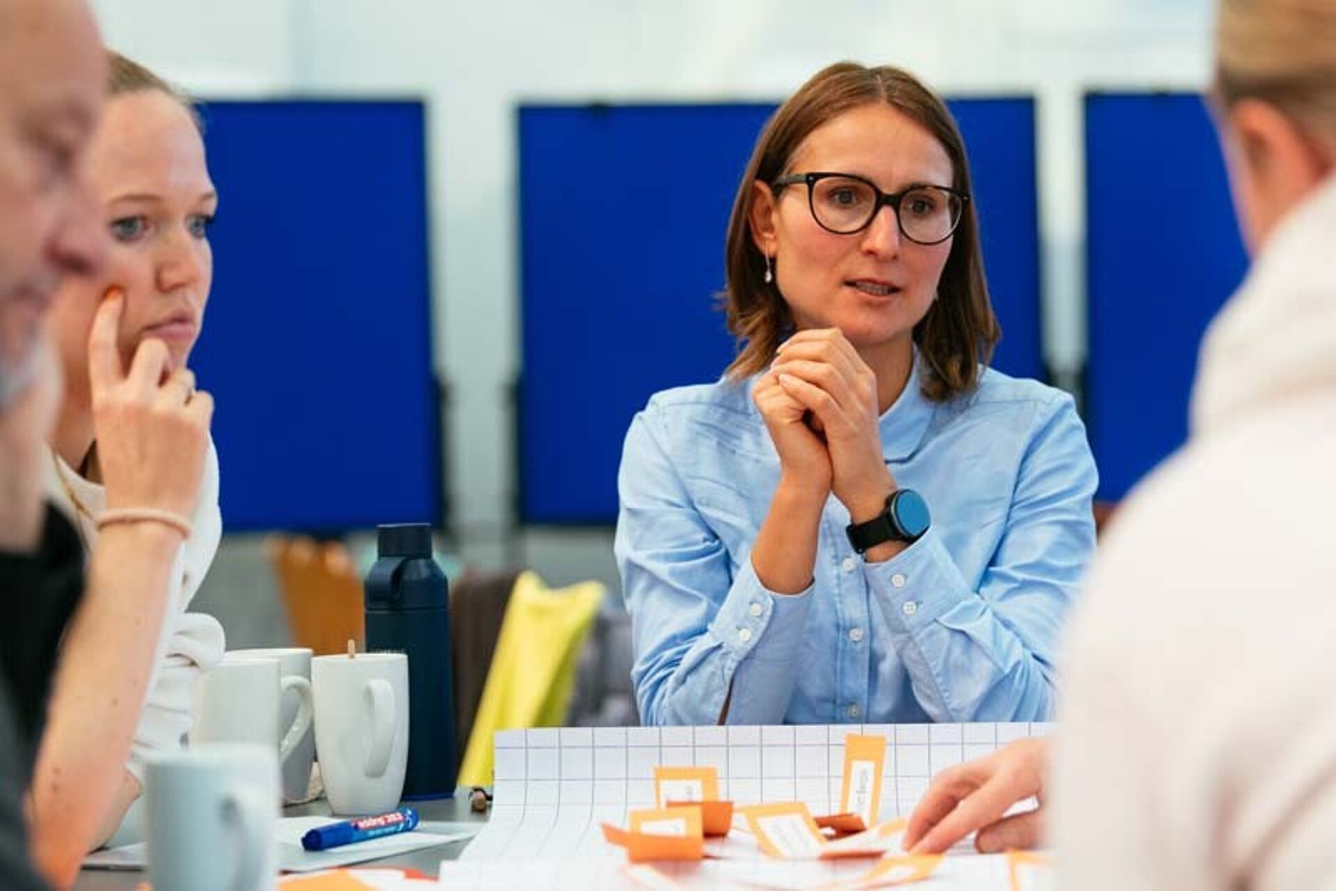 
                                                Eine Teilnehmerin spricht am Arbeitstisch
                                            