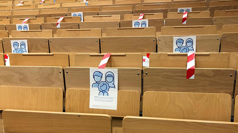 Hörsaal, in dem an einigen Sitzen Plakate zum Thema Gewalt gegen Frauen hängen