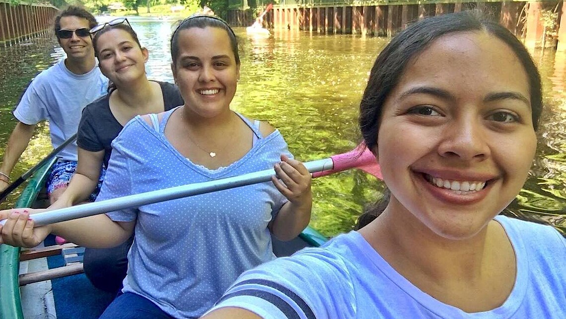 Female students smiling into the camera in a canoe on the water