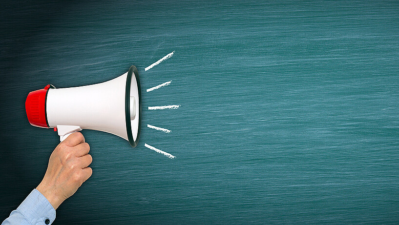 Megaphone with hand on green chalkboard background