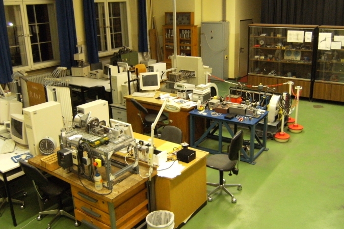 Blick in den Laborraum F122 weit vor dem Umbau 2009. Alte Rechnermonitore gemischte alte Möbel mit Prüfgeräten, im Hintergrund der Kupplungsprüfstand.
