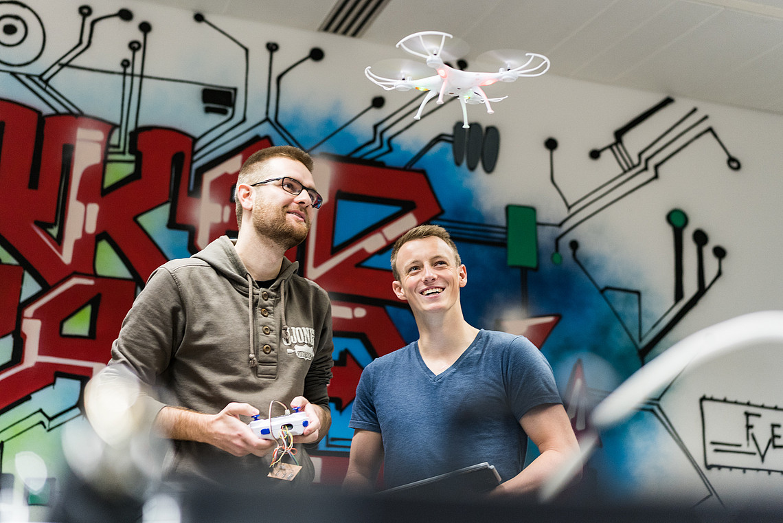 Makerspace und Drohnenprojekt, zwei Studenten vor bunter Wand
