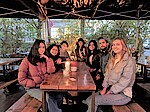 Sieben junge Studierende sitzen draußen an einem Tisch im Restaurant El Tigre in Hamburg und lächeln in die Kamera