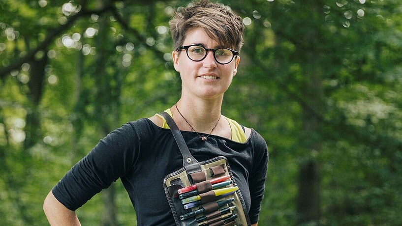 Female student posing outside with pens and pencils