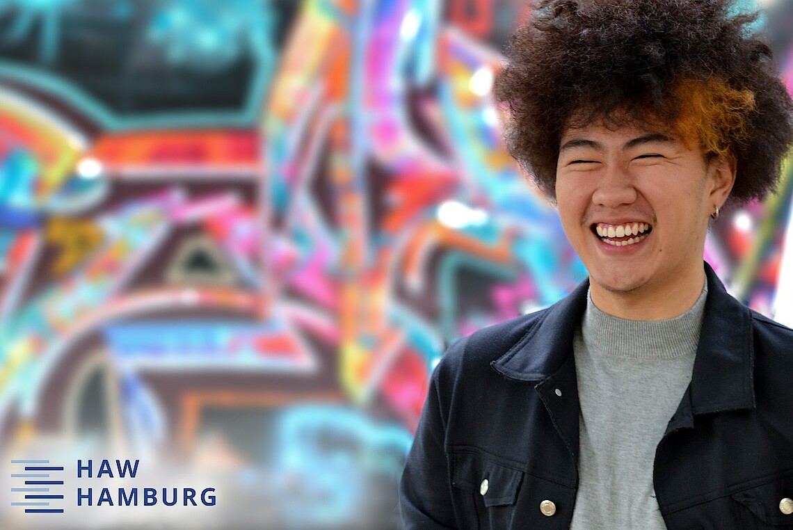 Male student standing in front of a wall with graffiti