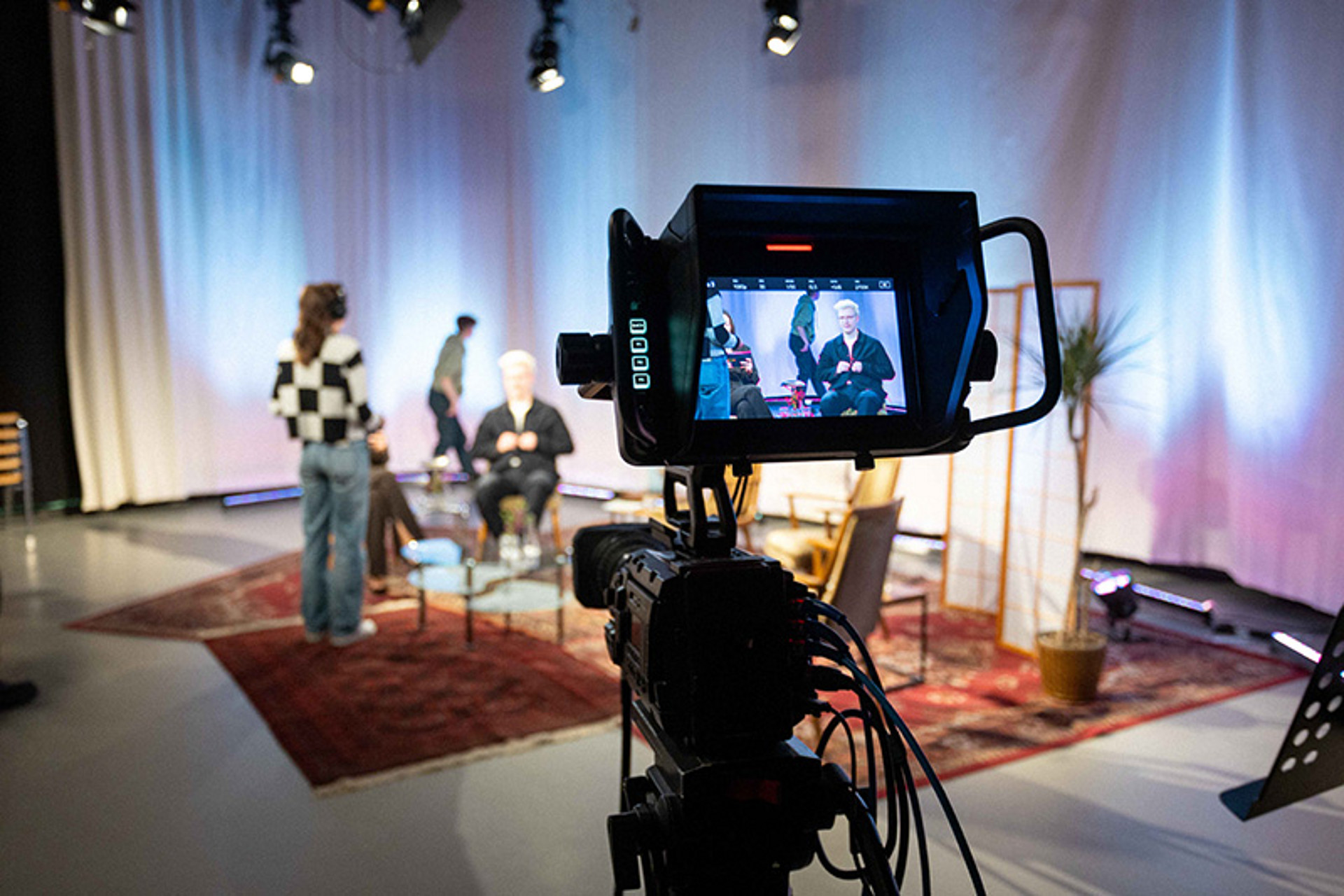 
                                                Das Talkshow-Setting zu sehen durch eine Kameralinse.
                                            